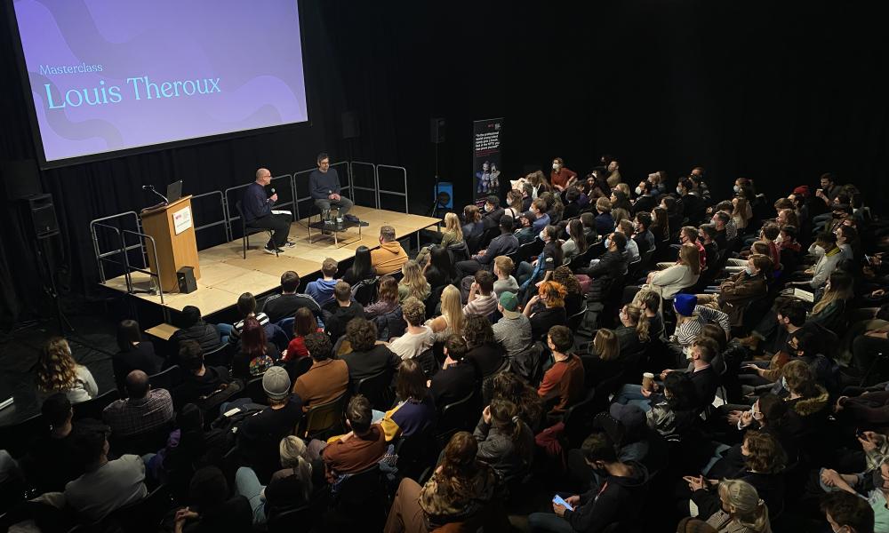 crowd of students listening to Louis Theroux sat on stage